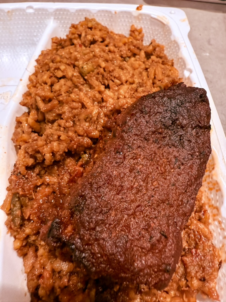Beef Jollof Rice with tender beef chunks in takeout container