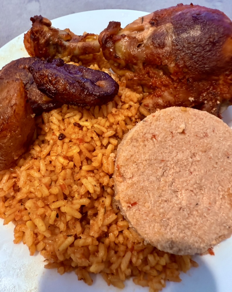 Spicy Jollof Rice with grilled chicken, plantains and moi moi